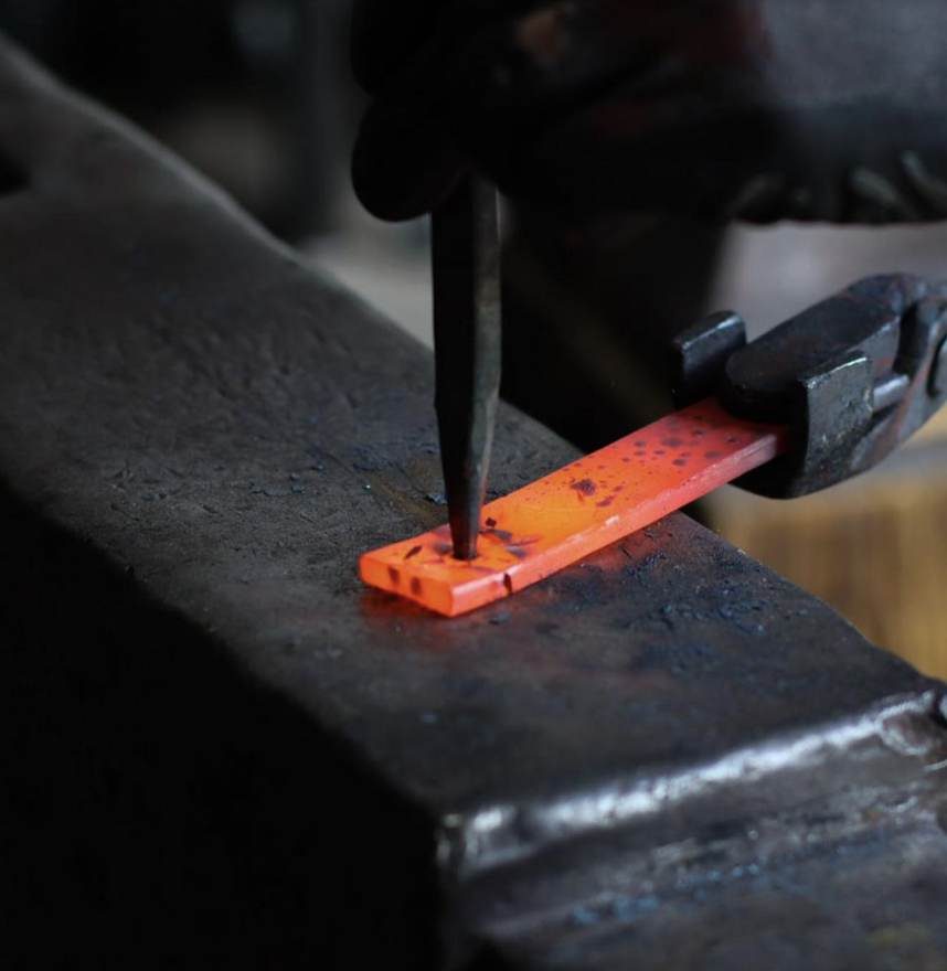 Hot steel being punched on the anvil
